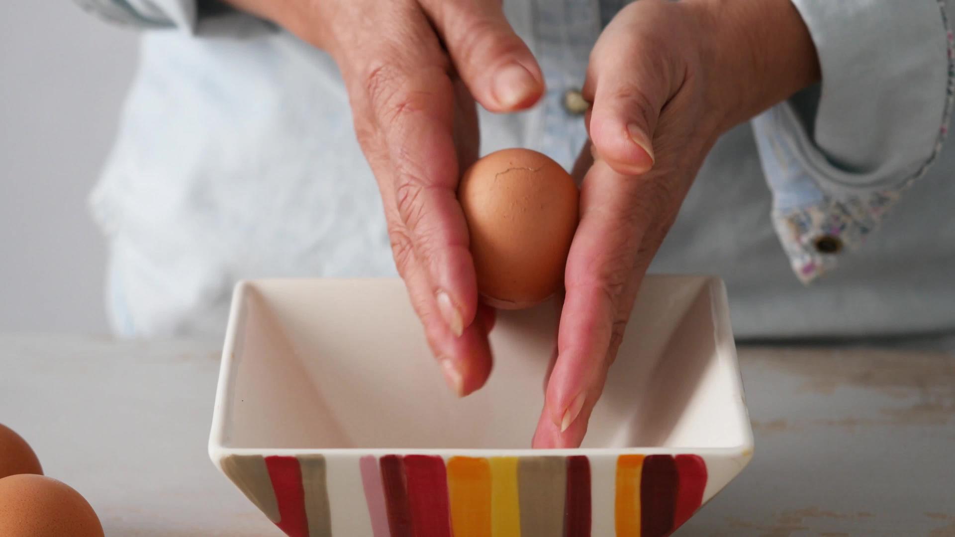 关闭女人的手壳一个煮熟的鸡蛋视频的预览图