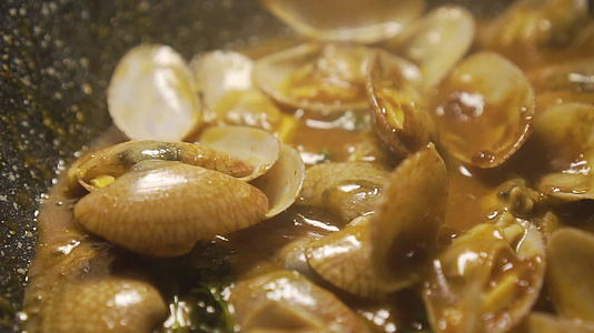 有人在锅里搅拌原料用烤辣椒酱做的炸蛤慢慢移动视频的预览图