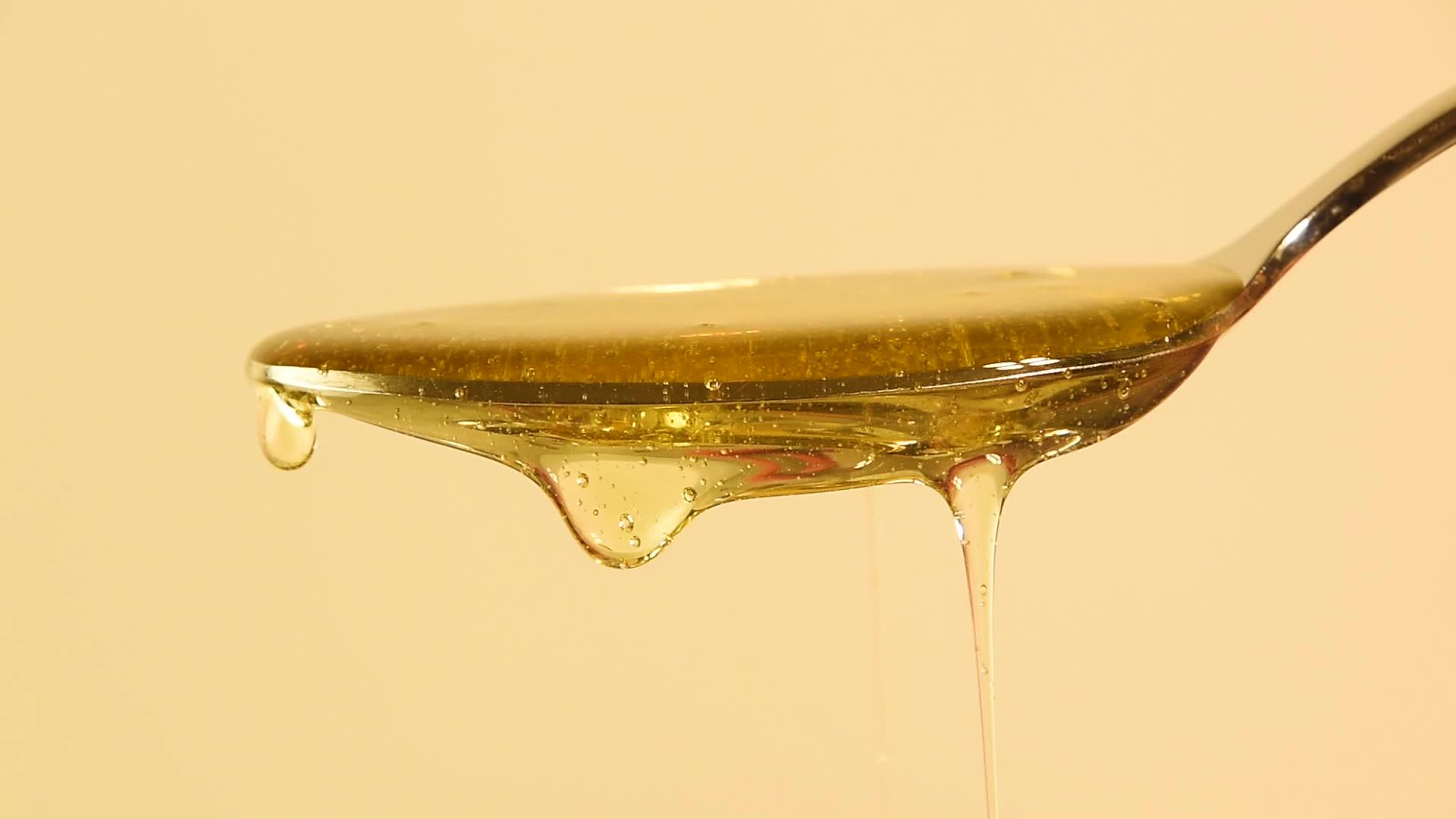 密封的蜂蜜从米边的金属勺子中流出视频的预览图