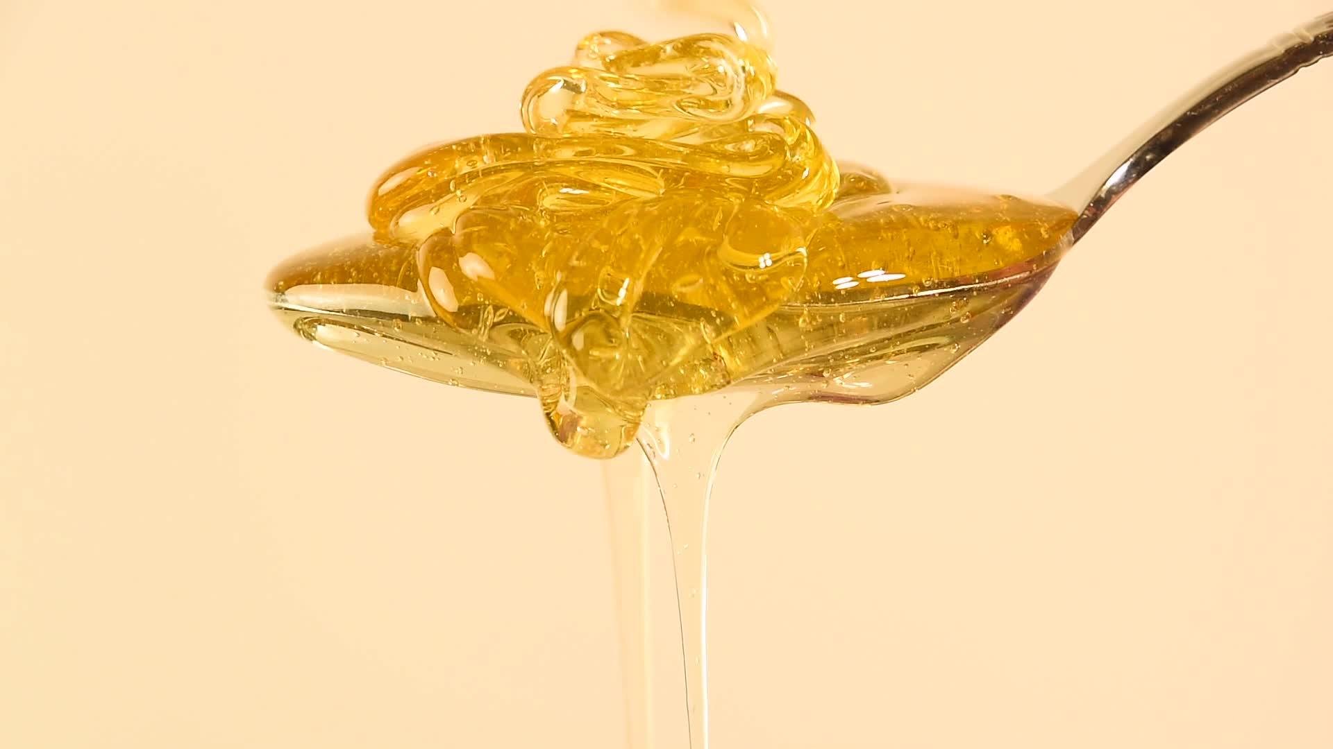 密封的蜂蜜从米边的金属勺子中流出视频的预览图