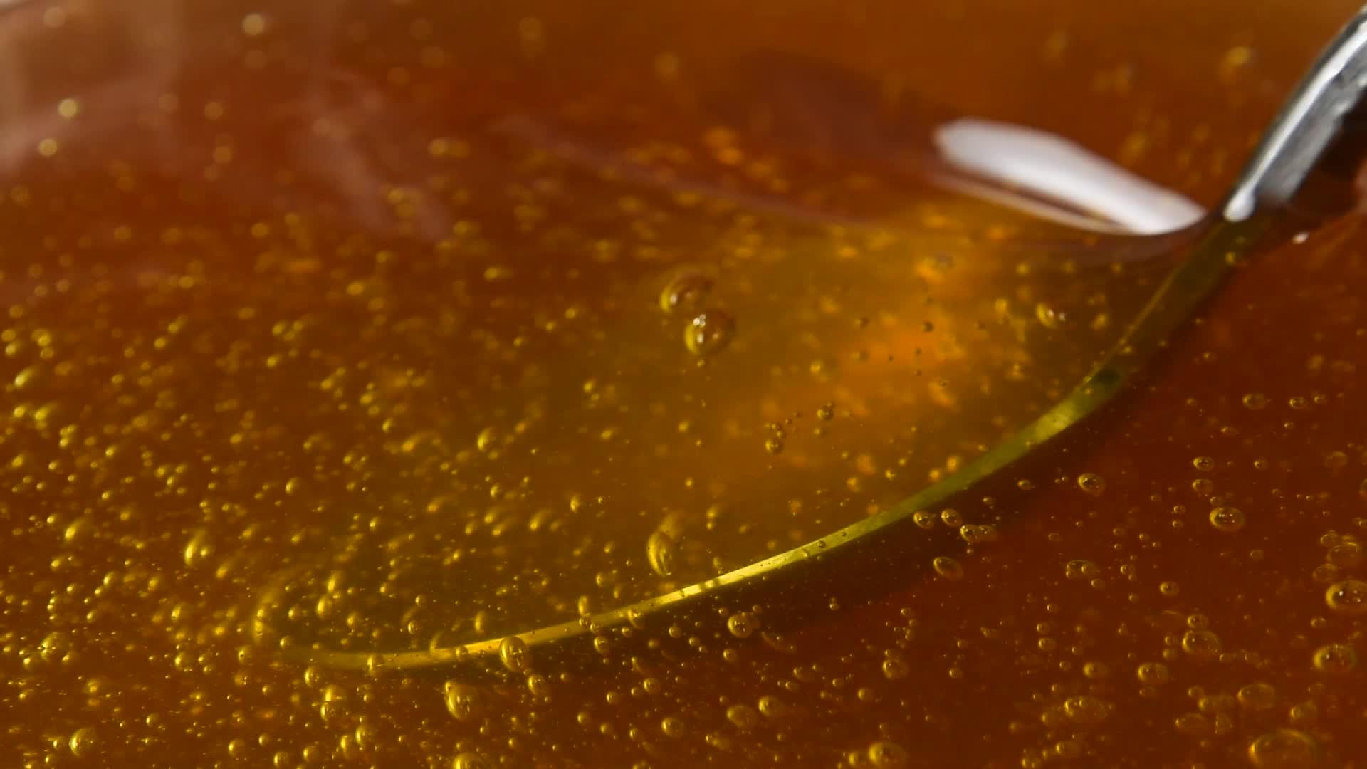 关闭蜂蜜碗中旋转的金属勺子视频的预览图
