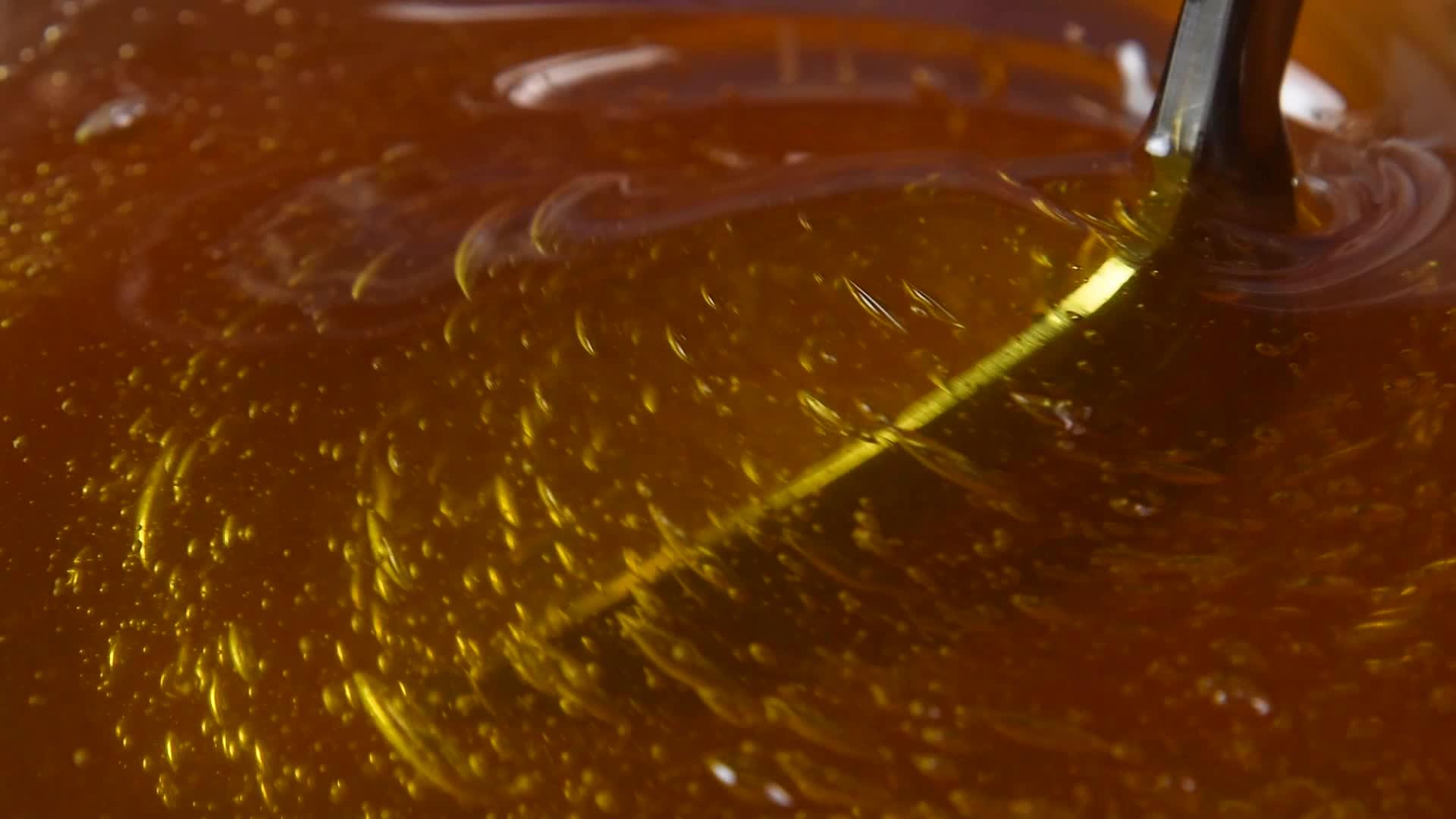 关闭蜂蜜碗中旋转的金属勺子视频的预览图