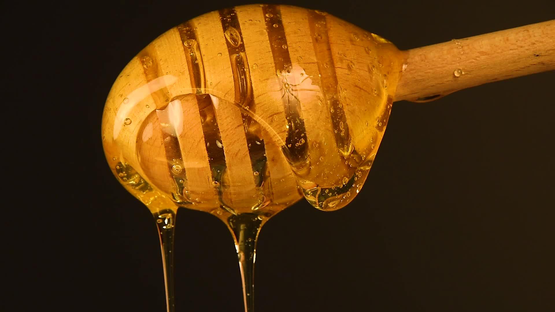封闭的蜂蜜从黑色木黄色的花朵中流出视频的预览图