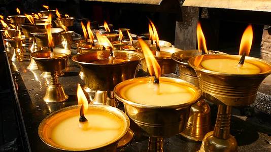 在寺庙里烧蜡烛看到金色的碗和燃烧的油蜡视频的预览图