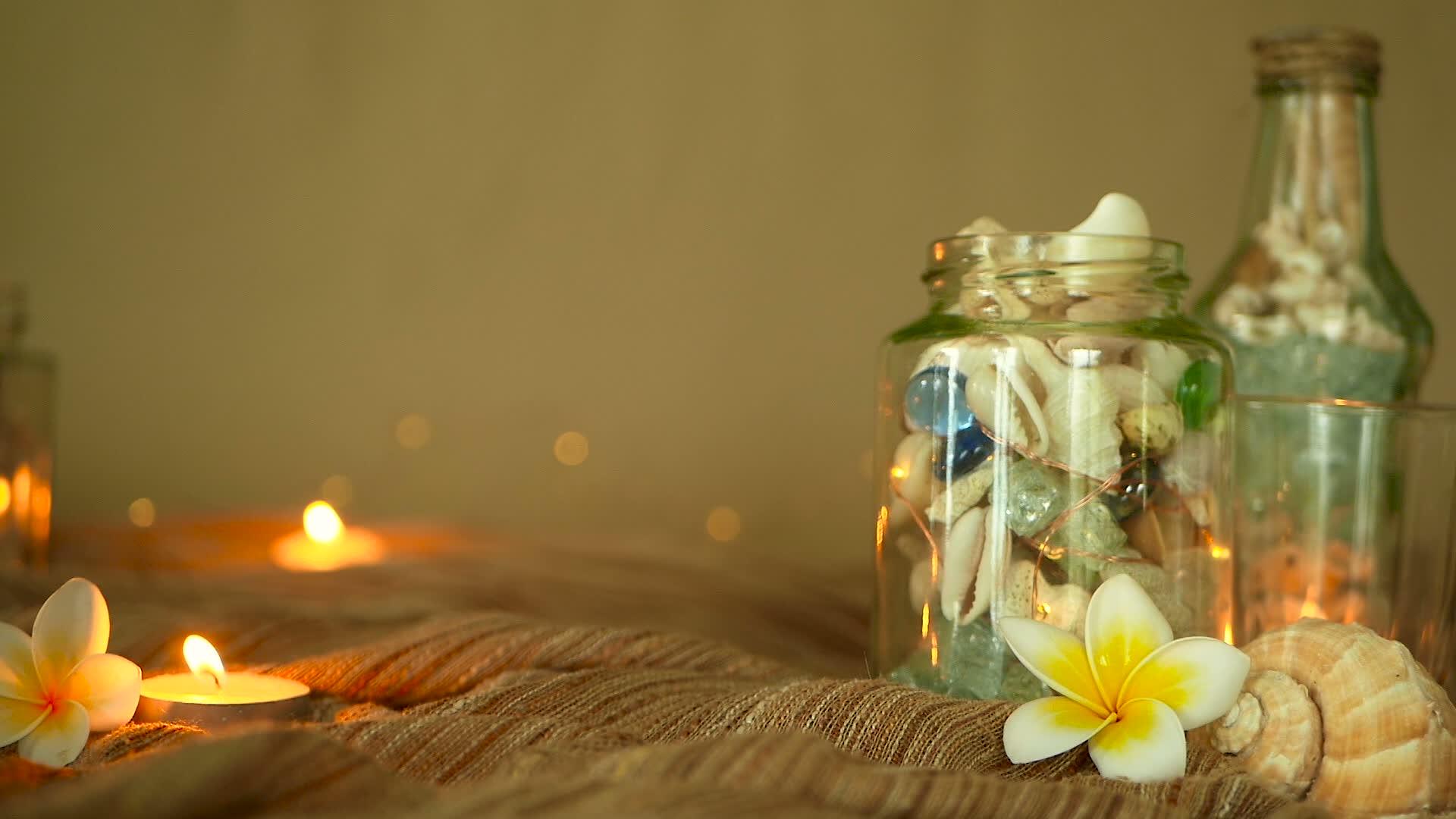 装满贝壳珊瑚的海洋物品、带蜡烛灯的花粉和装饰花的玻璃瓶视频的预览图