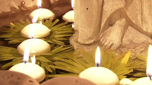 点燃的蜡烛慢慢地漂浮在寺庙的水中视频的预览图