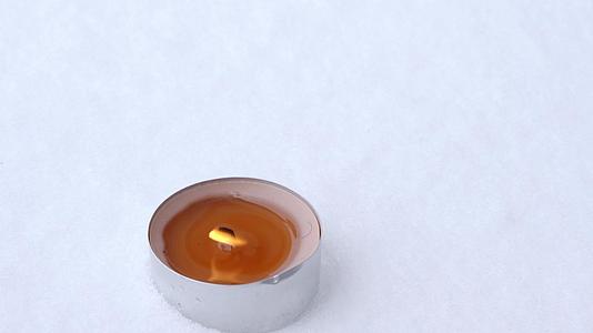 锡罐里的蜡烛可以在冬天的雪中燃烧关闭顶部的风景视频的预览图