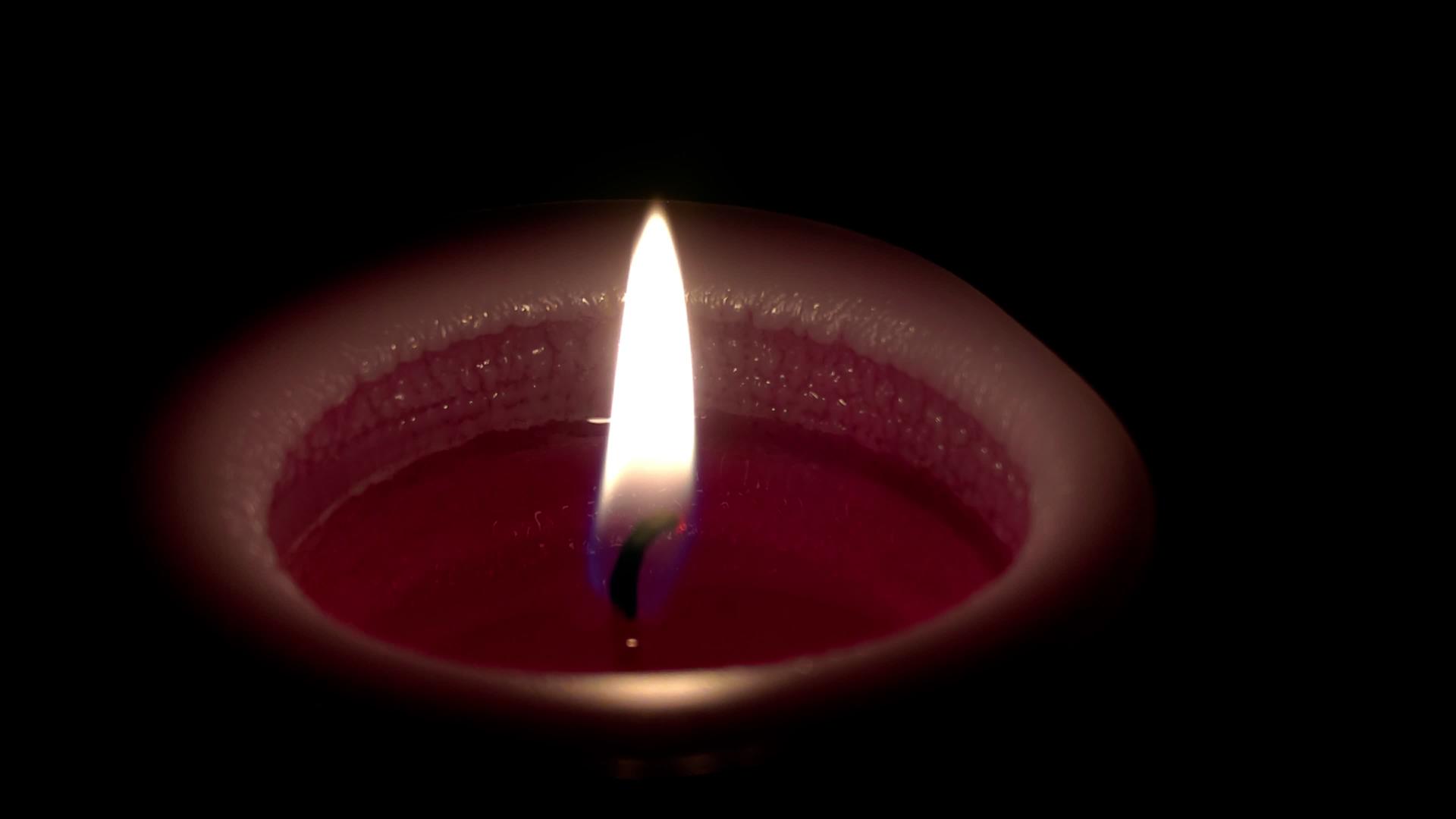 在黑暗的背景下紧紧地关在燃烧的蜡烛上视频的预览图