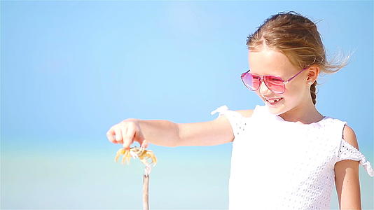 可爱的小女孩在海滩上抱着螃蟹视频的预览图