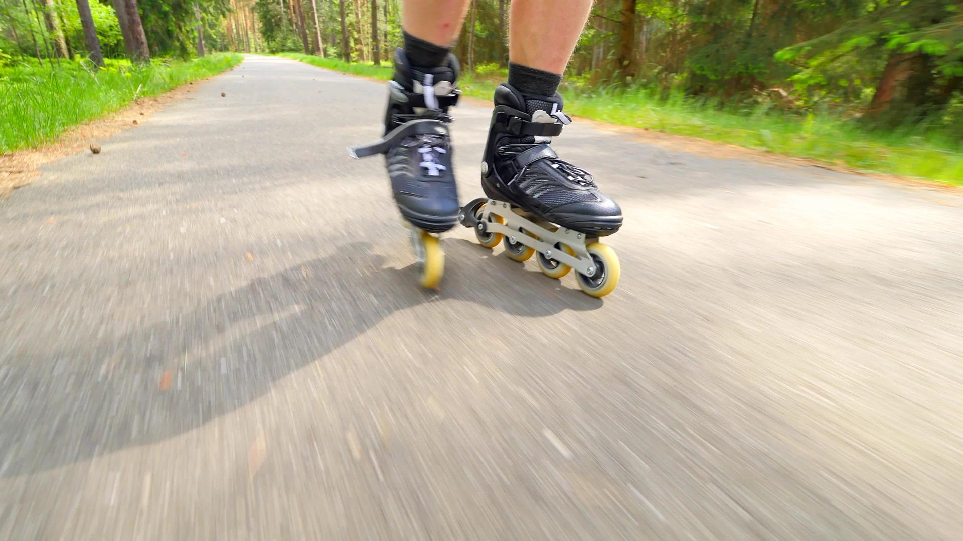 男子在森林沥青路上滑过滚轮滑雪近距离观察内衬靴的速度视频的预览图