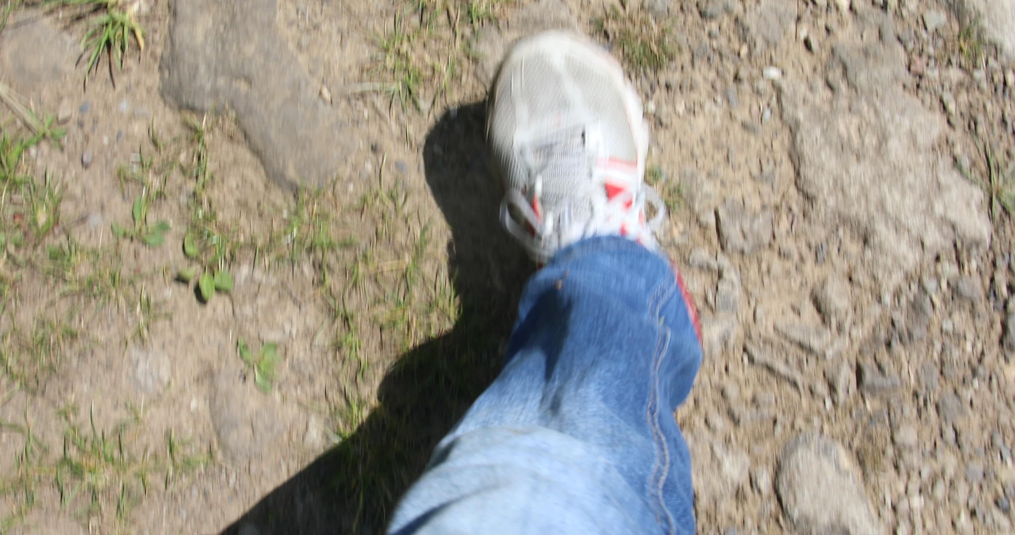 穿着运动鞋和牛仔裤的男人的腿穿过干燥的草地视频的预览图