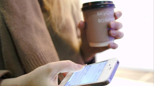 带咖啡的步行妇女在智能手机上发短信视频的预览图