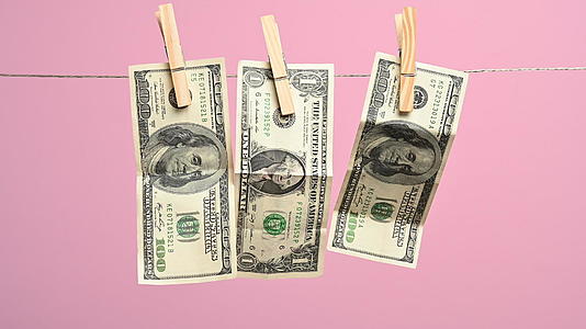 挂在晾衣绳上的美元有一个粉色背景洗钱概念视频的预览图
