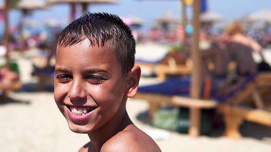 快乐的西班牙男孩在海滩上对着镜头电影微笑Dof视频的预览图