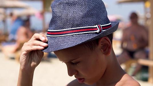 快乐的西班牙男孩在海滩上戴着帽子对着镜头微笑Dof视频的预览图