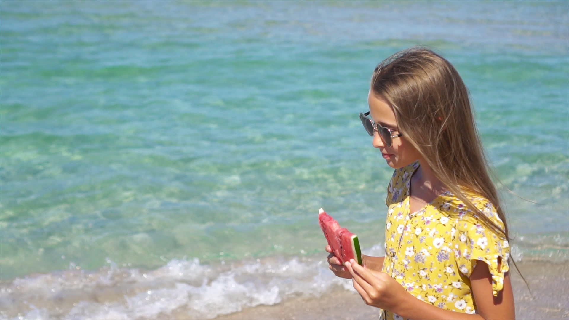 快乐的女孩在沙滩上玩吃西瓜视频的预览图