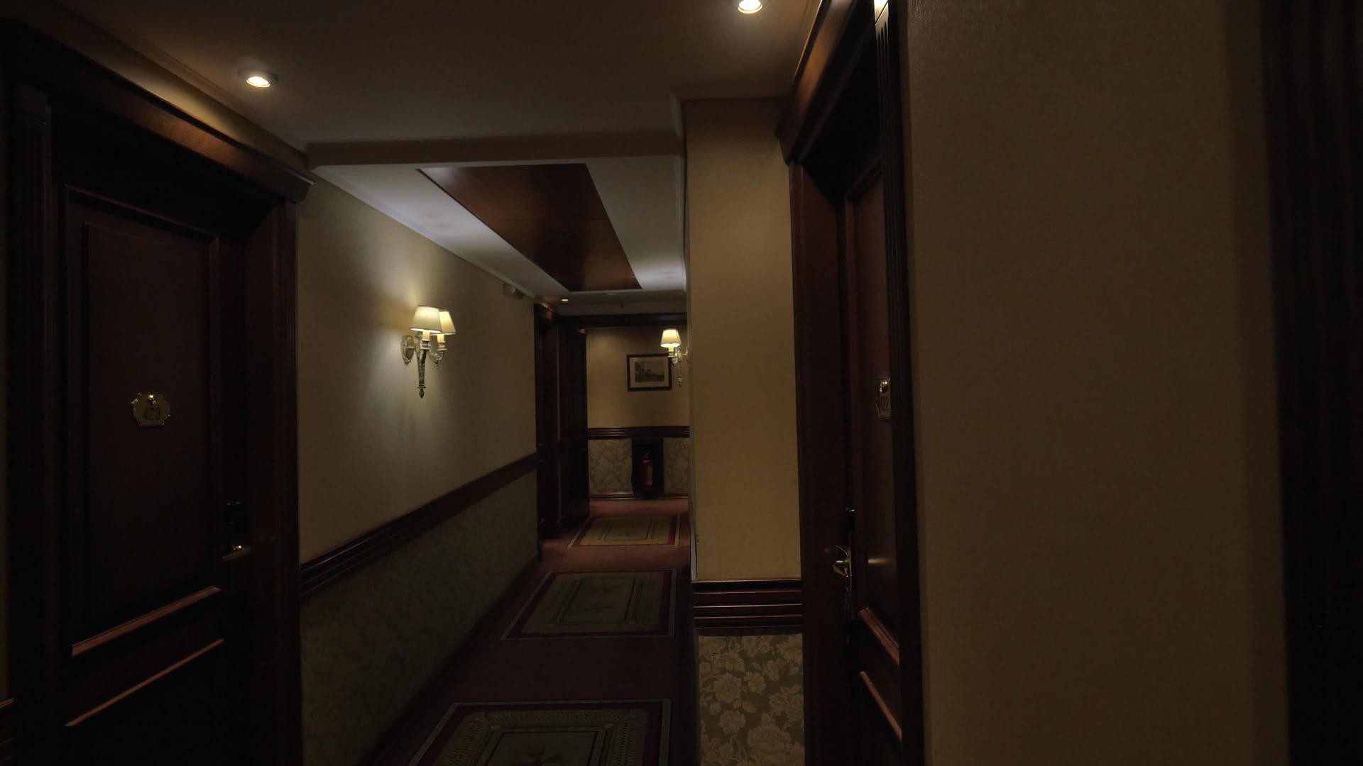 看到长长的旅馆走廊有灯光和房间门视频的预览图