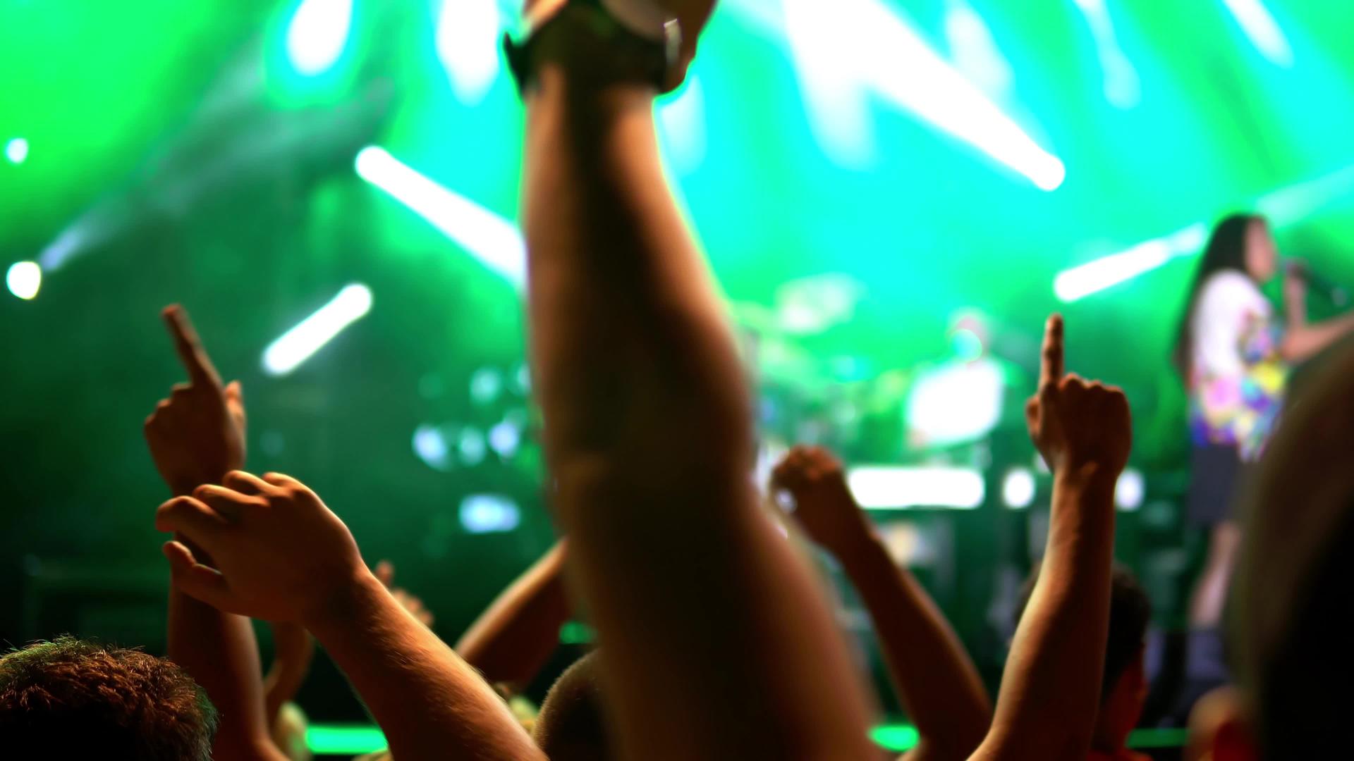 在音乐节上 观众举起手 灯光从舞台上方流下来 专注于公开音乐会视频的预览图
