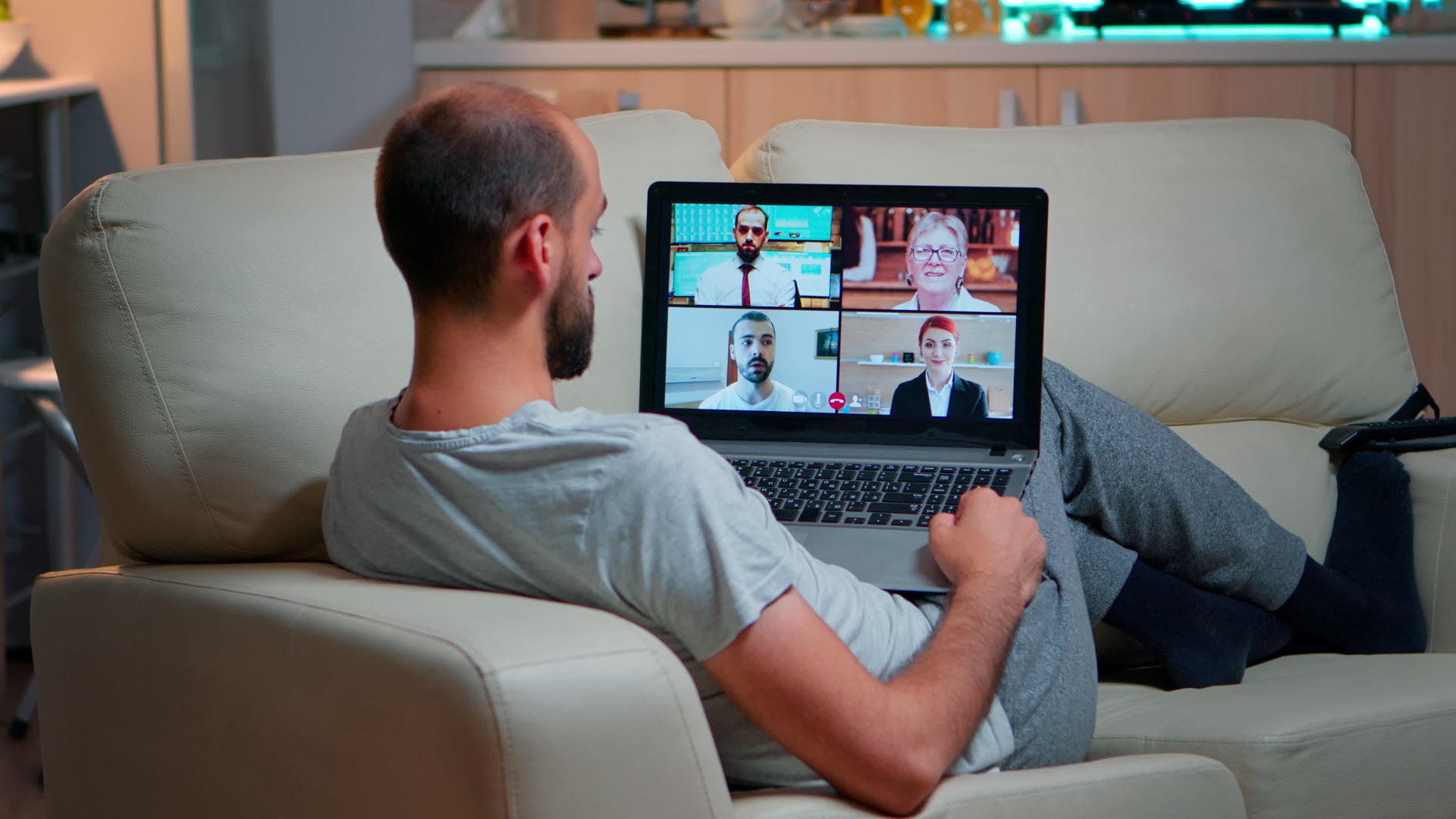 疲惫的男人舒服地坐在沙发上和队友聊天视频的预览图