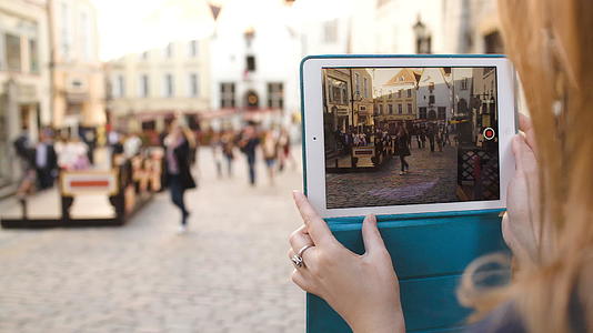 女性用平板电脑拍摄长高的街道视频然后观看视频的预览图