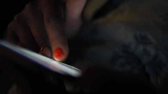 女人用平板电脑在黑暗中航行他的手指和复制空间闪闪发光视频的预览图