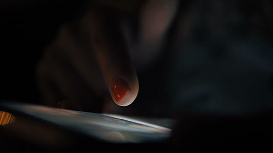 现代智能手机中的女性使用交互式触摸屏在夜间显示低光教育视频的预览图