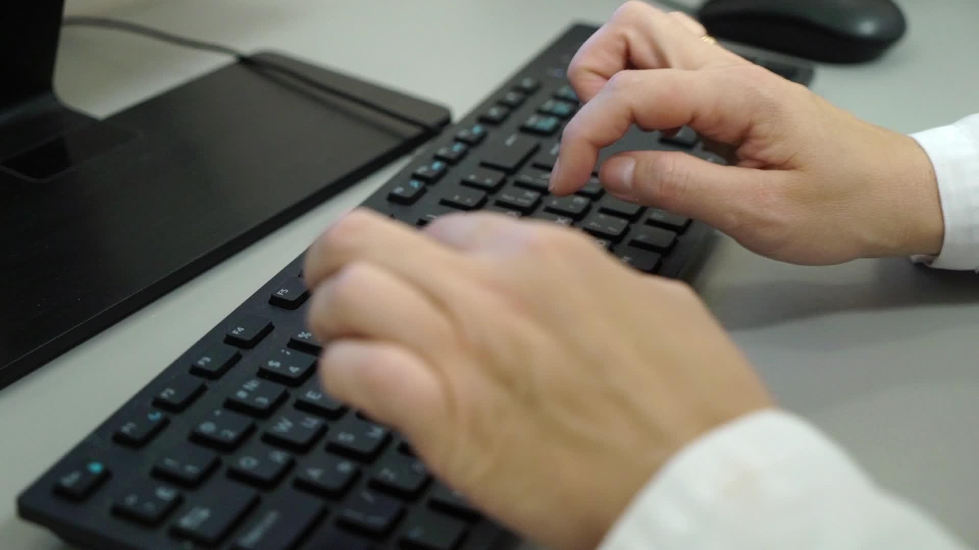 女医生给病人输入医疗收据在诊所的电脑里工作视频的预览图