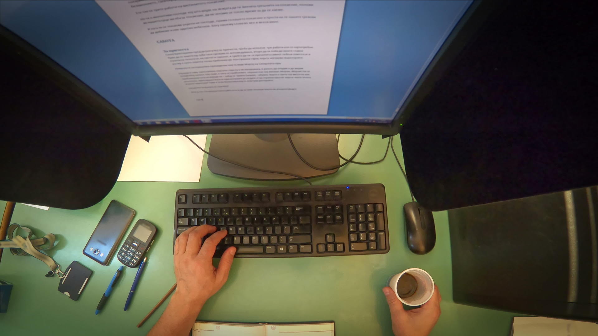 男人在台式电脑键盘上打字在办公室喝咖啡的顶视图联网视频的预览图