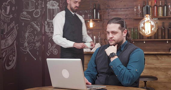 英俊的男性自由职业者在笔记本电脑上工作喝咖啡视频的预览图