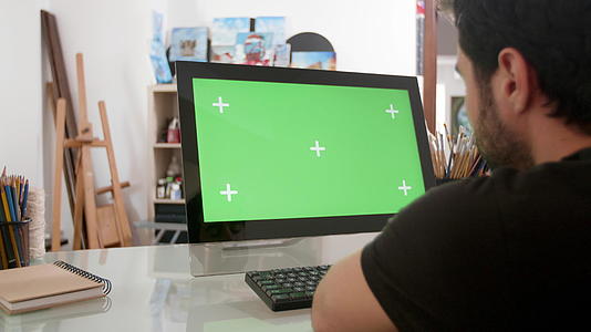留胡子的人看着电脑上的绿色屏幕视频的预览图