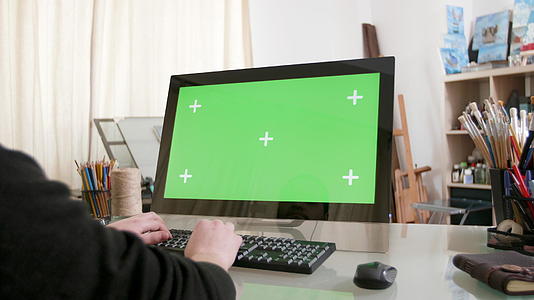 一个在电脑上用绿色屏幕工作的人慢慢拍摄镜头视频的预览图