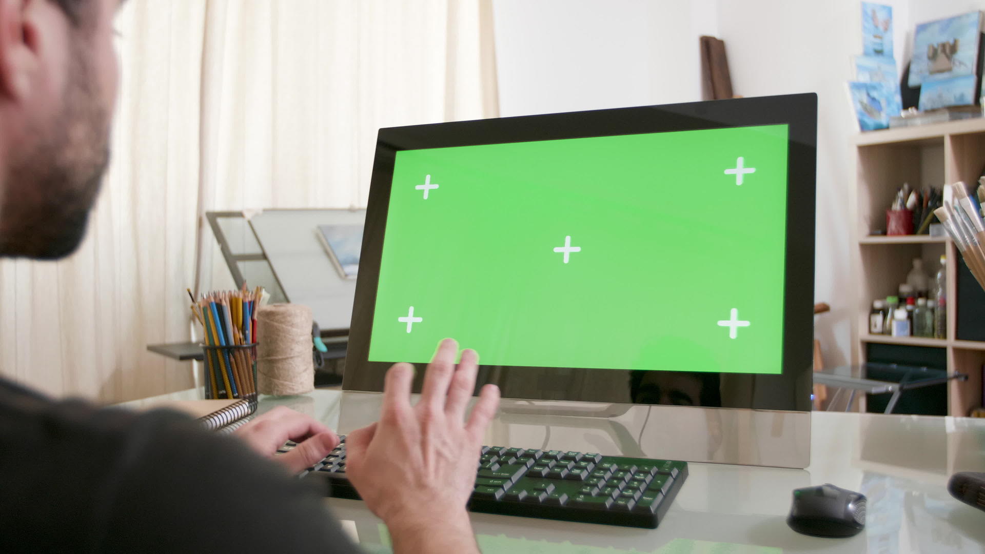 一位年轻的艺术家在他的电脑上工作显示着绿色的屏幕视频的预览图