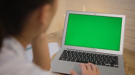 绿色电脑屏幕女孩坐在桌旁远程学习上网冲浪穿着衣服视频的预览图