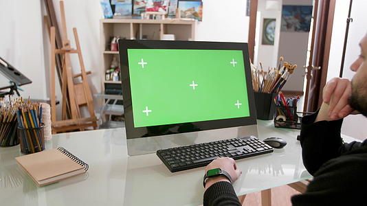 一个留着胡子的男人有着艺术的外表在绿色的屏幕上观看视频视频的预览图