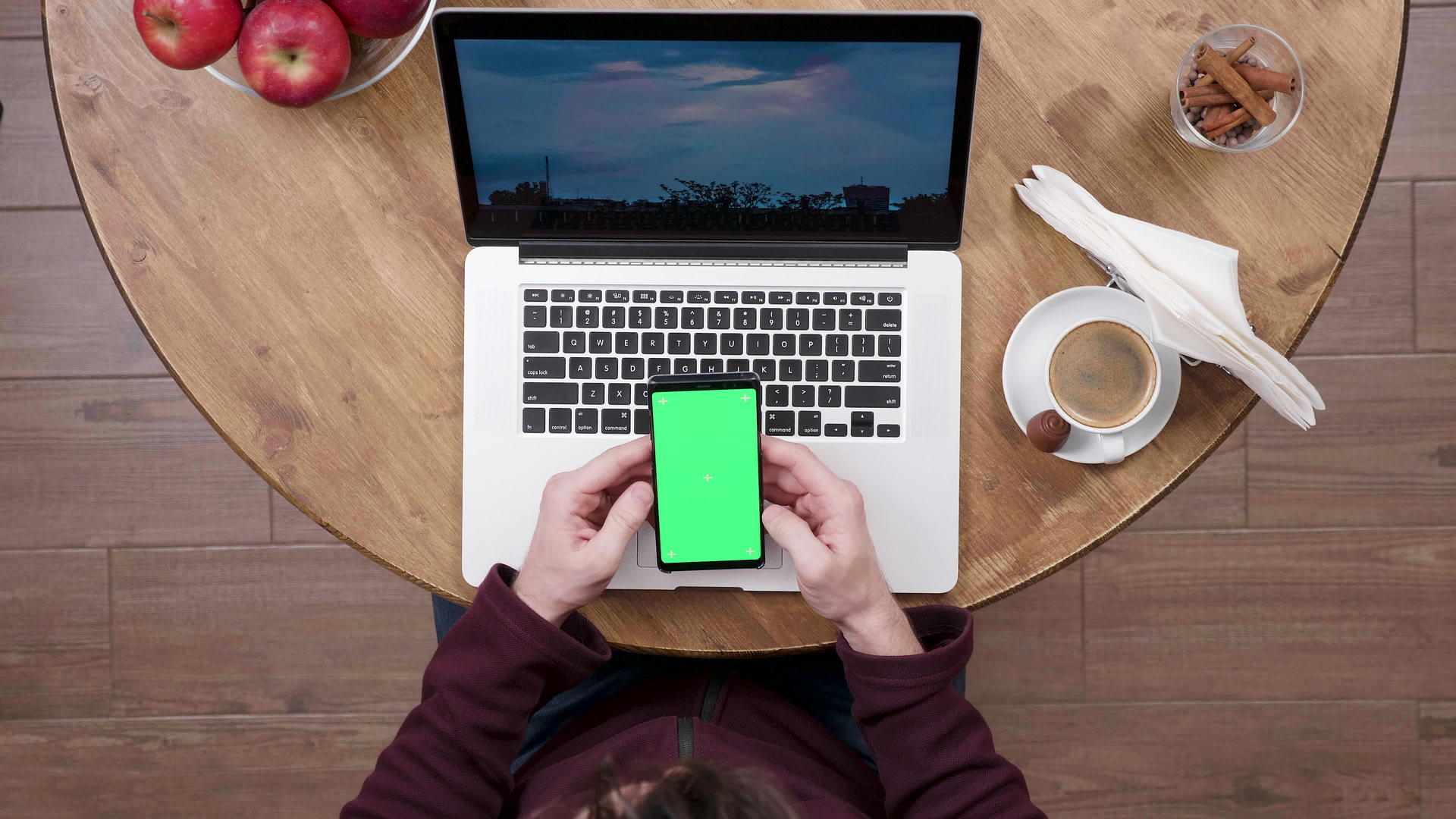 一名男子在笔记本电脑前拿着一部带有绿色屏幕的智能手机视频的预览图