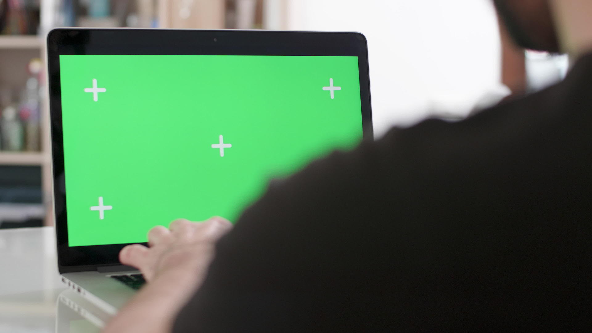 一个在笔记本电脑上用绿色屏幕工作的人的肩膀被射中视频的预览图