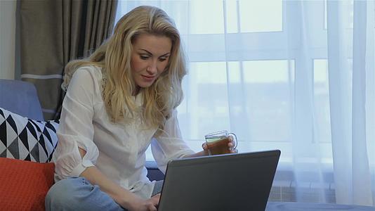 女人在家里的笔记本电脑附近喝茶视频的预览图
