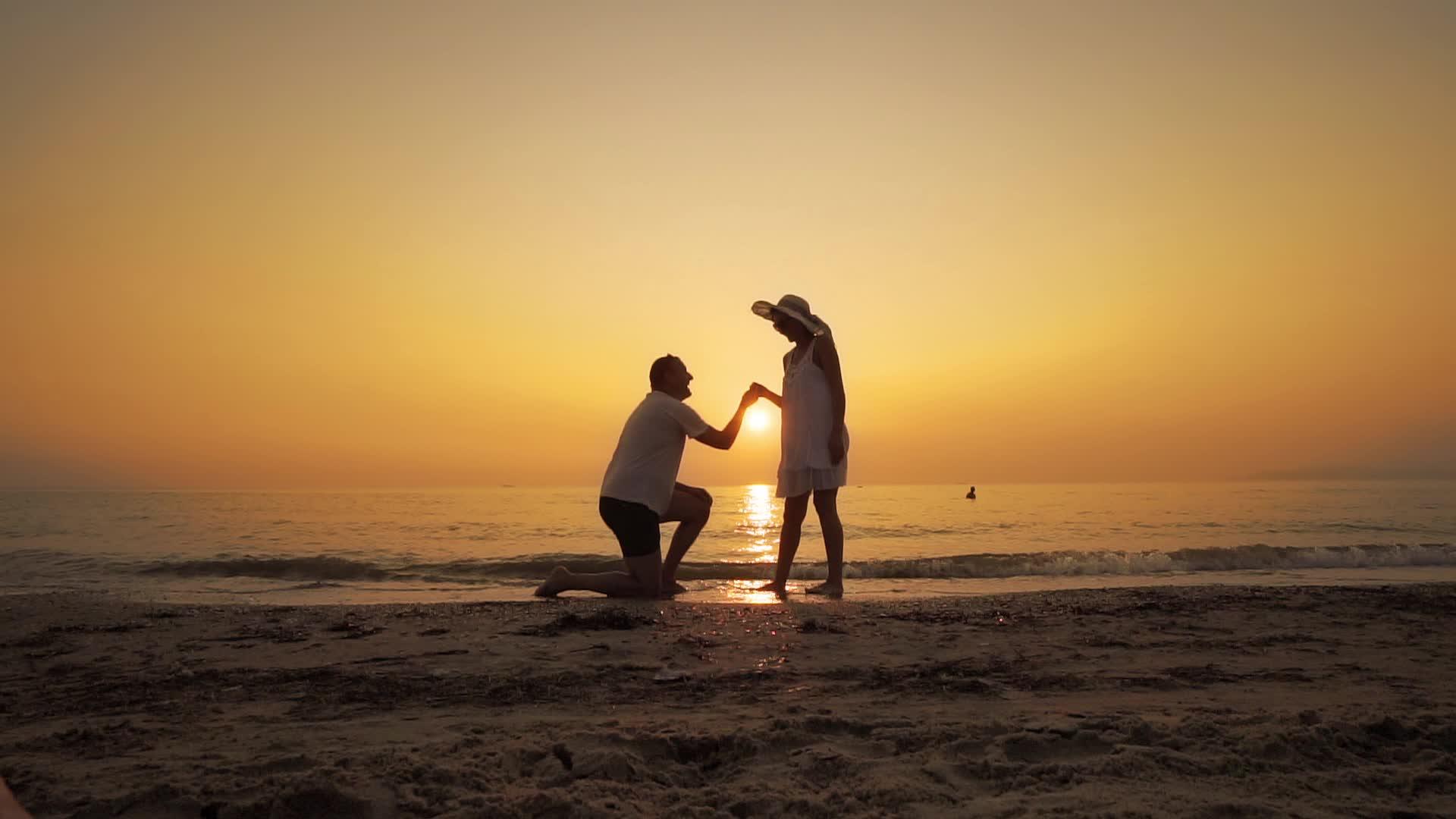 一个男人在日落时向海滩求婚视频的预览图