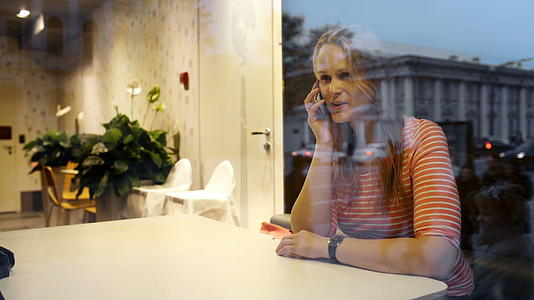 晚上咖啡馆里一个年轻女子的电话谈话视频的预览图