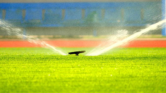 地下喷雾器给足球场浇水在炎热的夏天足球场上有一个草草的背景视频的预览图