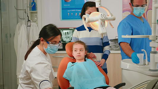 牙医和坐在口腔椅上的孩子交谈视频的预览图