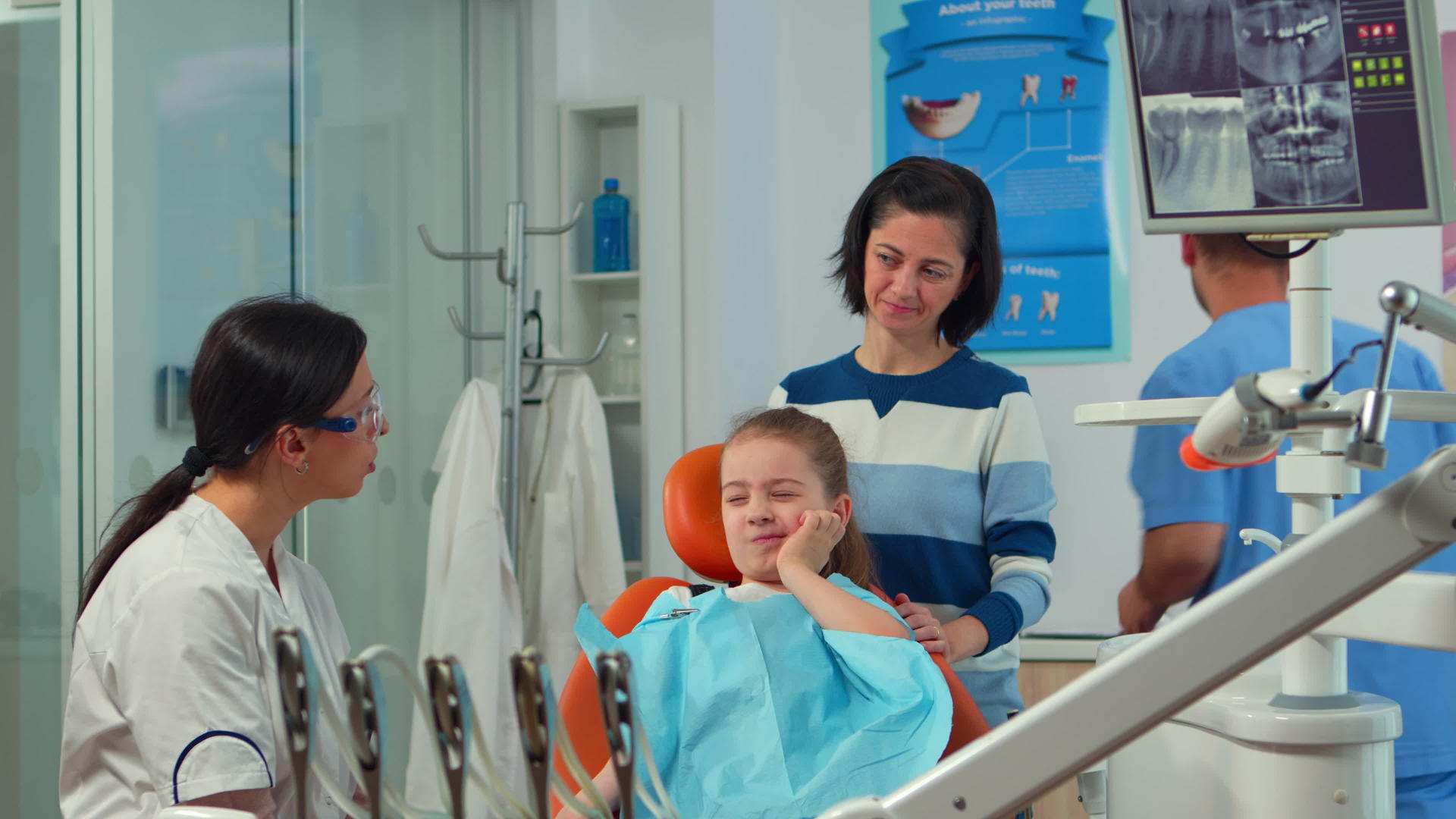 当牙医和母亲交谈时用孩子的手指指着影响牙齿的牙齿视频的预览图