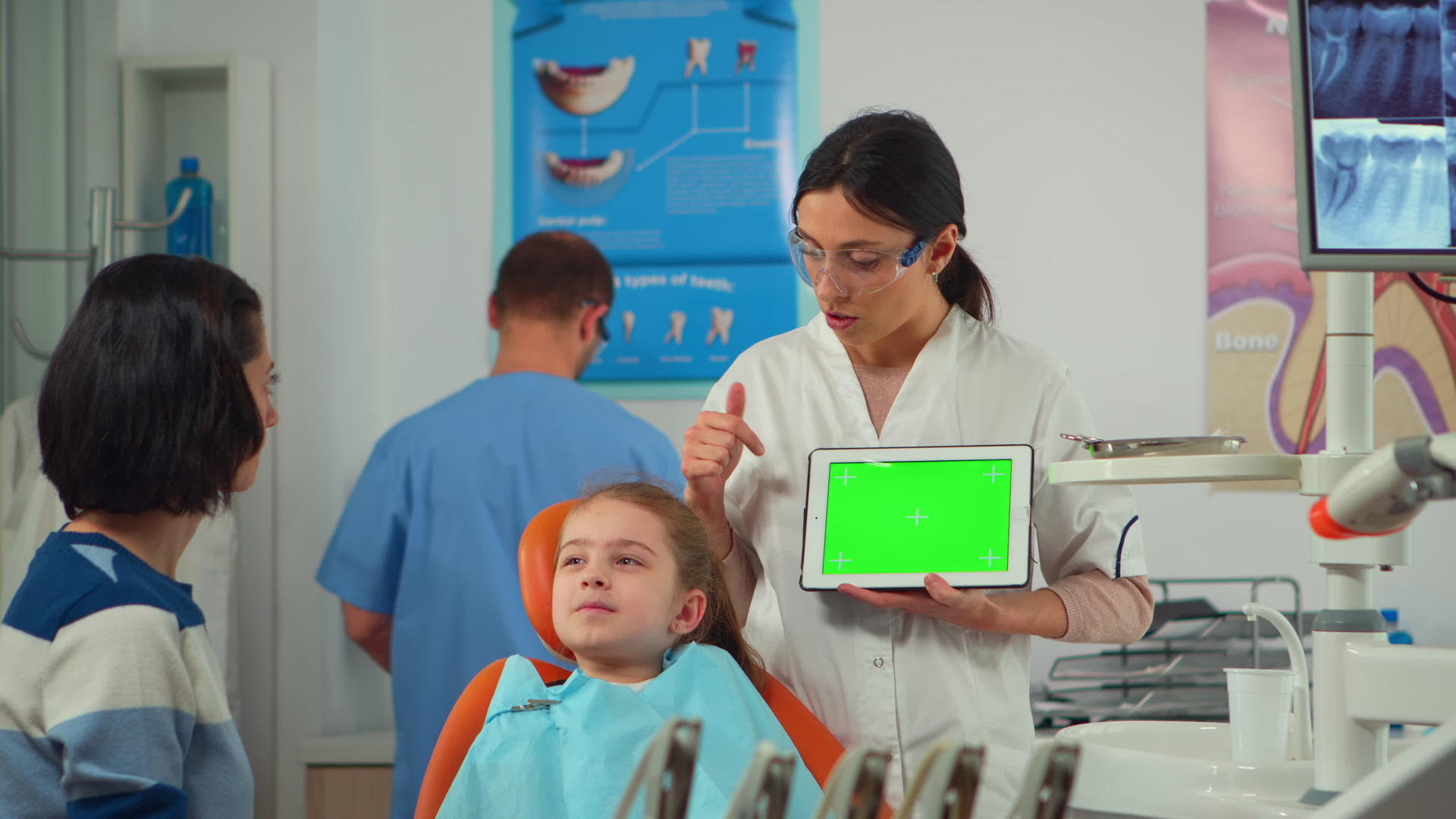 牙医向小病人的母亲展示绿色屏幕视频的预览图
