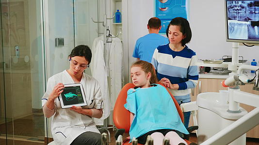 孩子们坐在口腔病理学的椅子上听儿科医生看药片视频的预览图