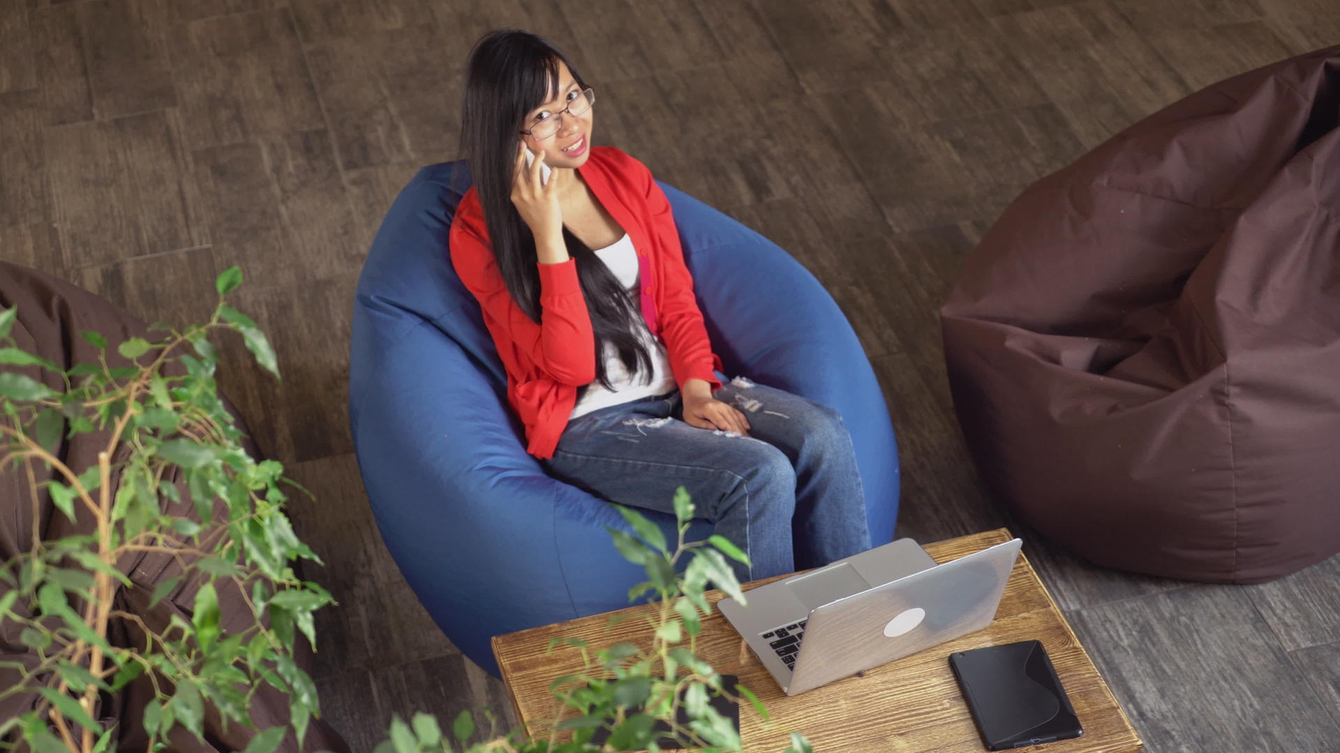 亚洲专业女性坐在彩色椅子上高视线下在智能手机上交谈视频的预览图