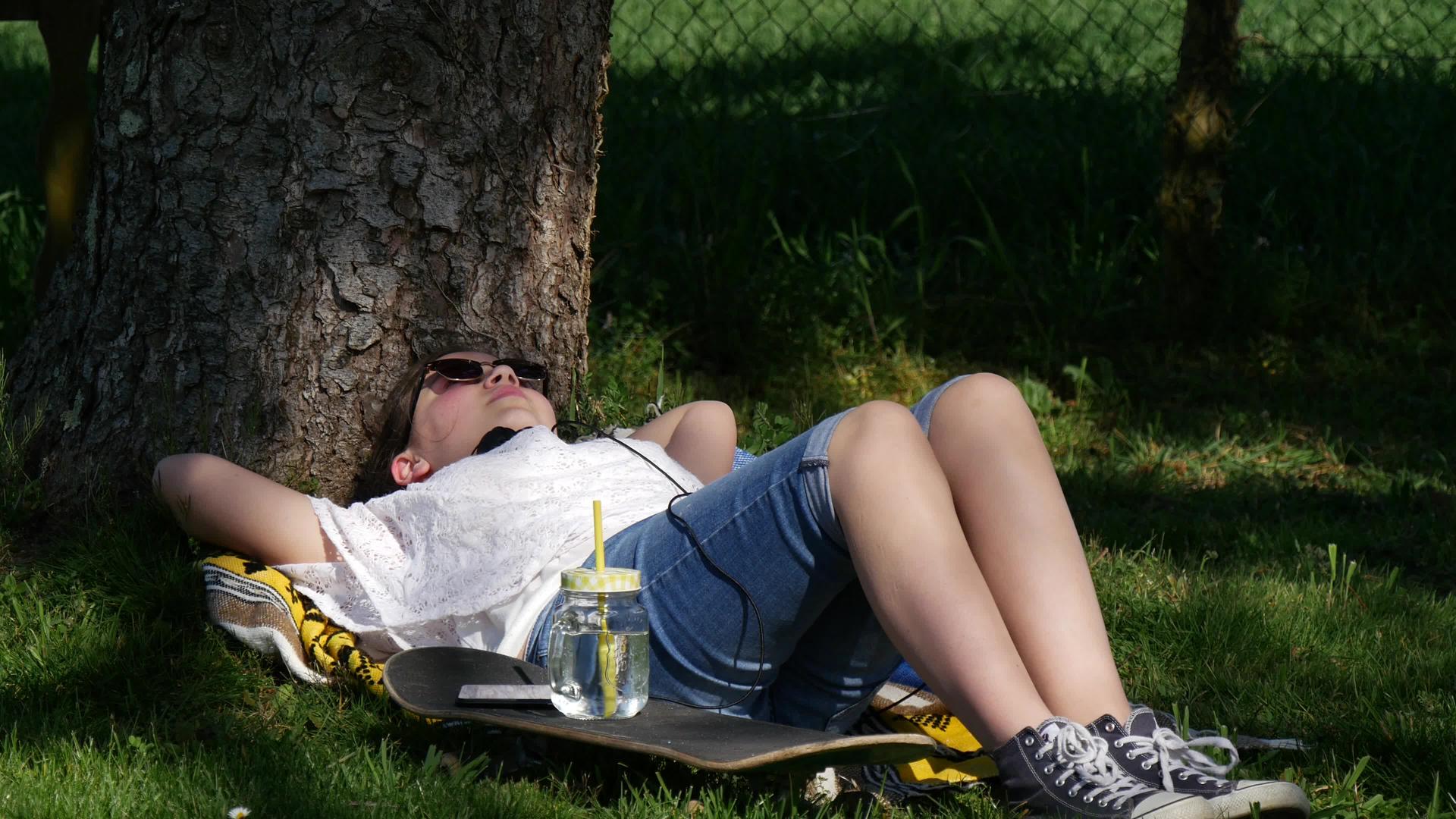 女孩躺在公园树旁的地上视频的预览图