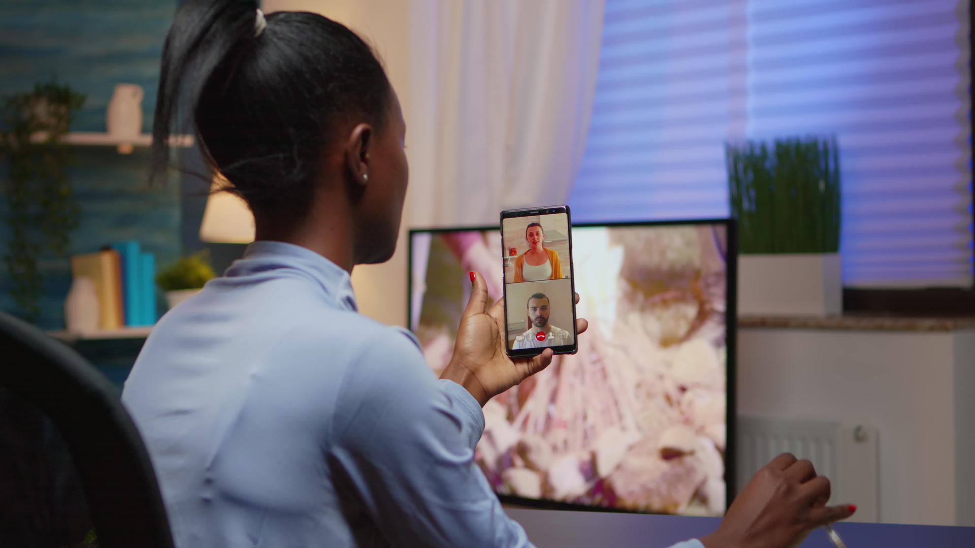 黑人年轻人在网络摄像头上与使用智能手机的家庭讨论视频的预览图