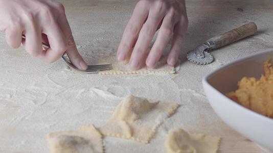 家庭主妇厨师用叉子制作馄饨素食自制面食tortelli视频的预览图