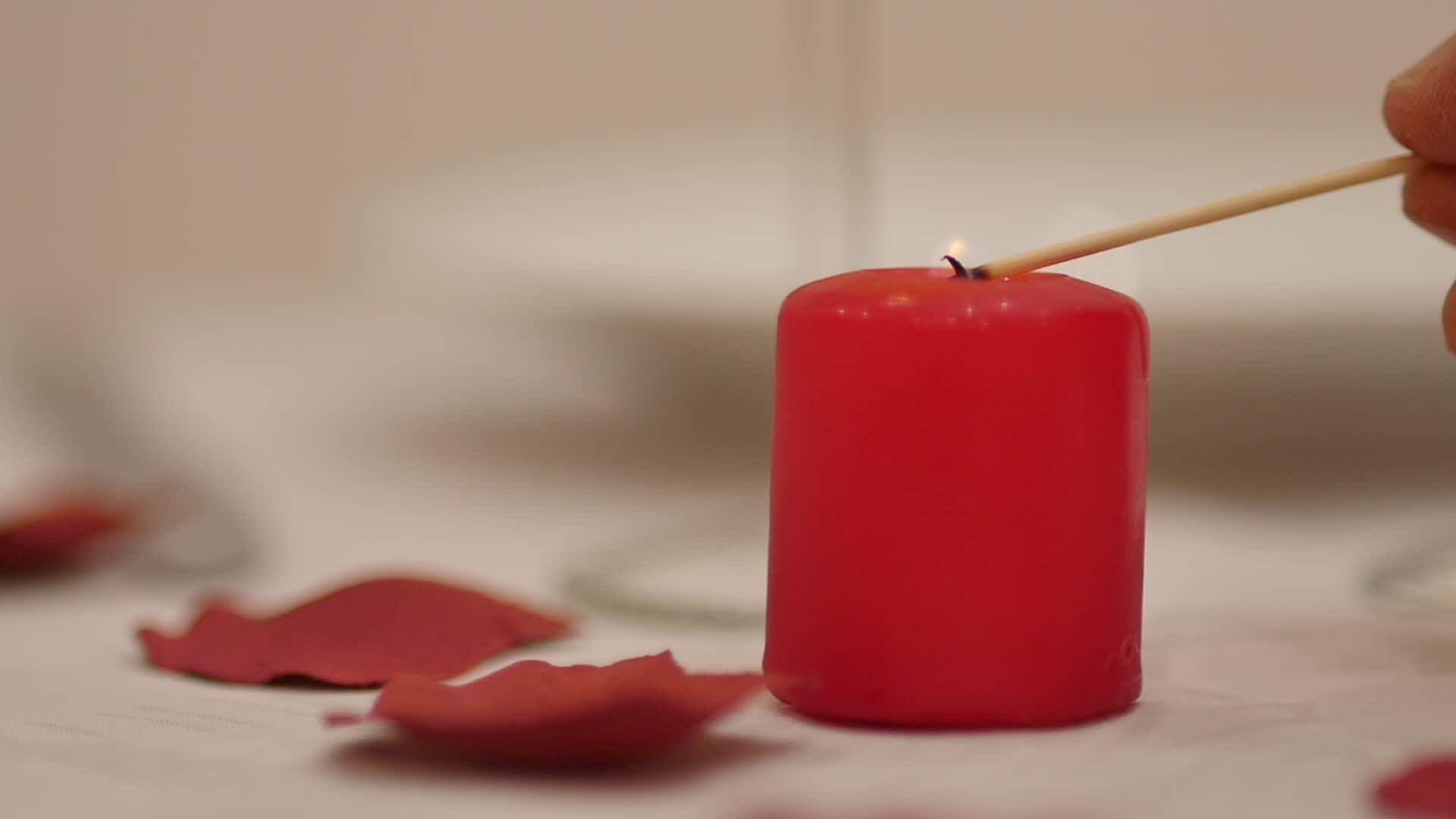 情人节餐桌上的男服务员或情人为浪漫的晚餐点燃红色的爱情蜡烛视频的预览图