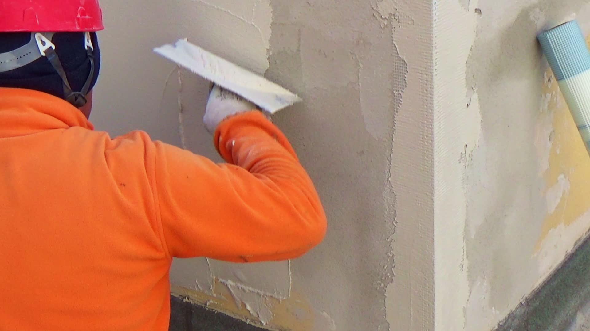 建筑工人在一堵墙上打石膏手里拿着美国的土筋视频的预览图